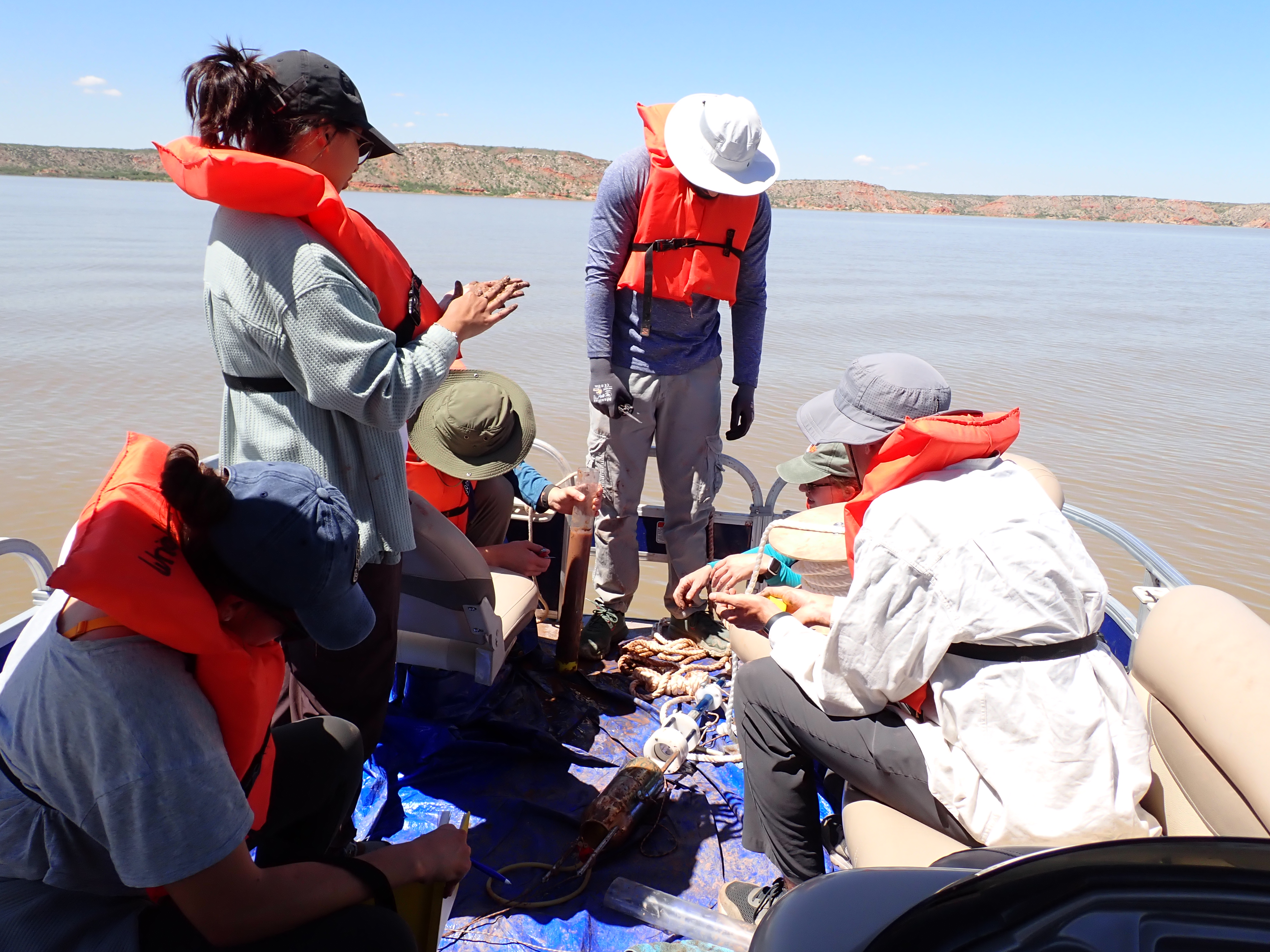Researchers conducting boat-based sediment sampling at Lake Meredith